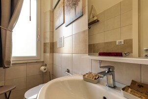 Un baño con lavamanos blanco, un espejo, toallero y ventana.