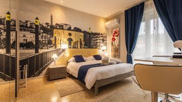 A hotel room with a bed, bedside tables, a desk, and a large window with curtains.