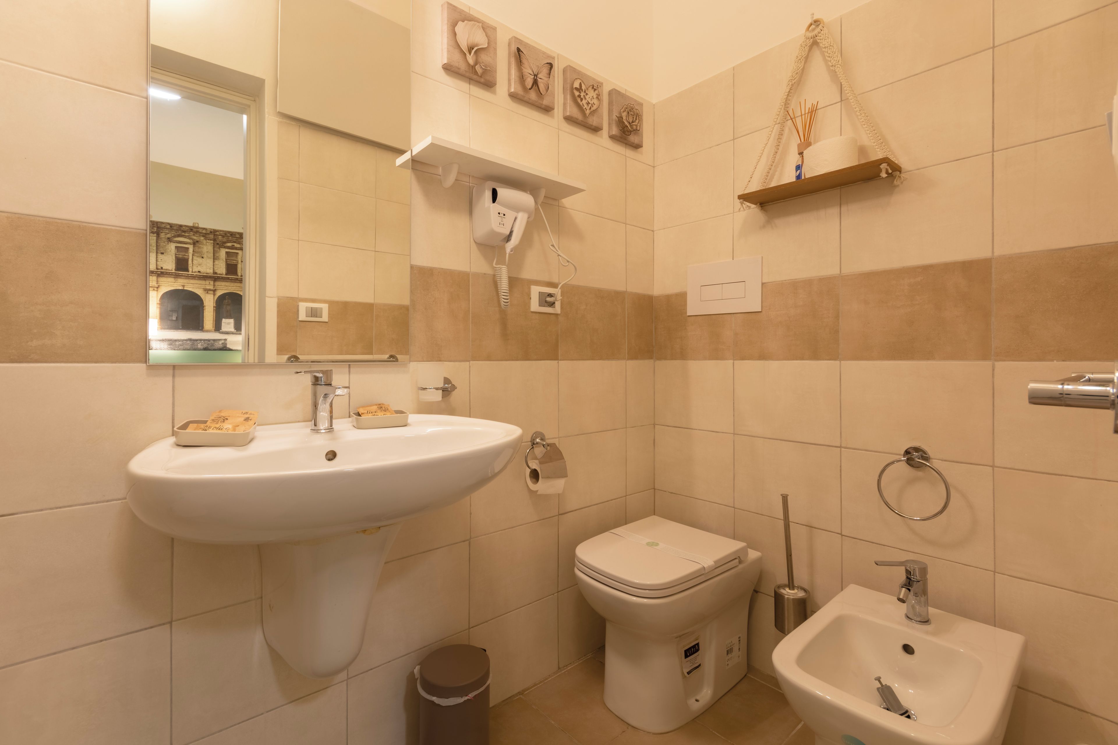 A bathroom with a sink, toilet, bidet, and a mirror.
