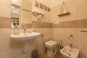 A bathroom with a sink, toilet, bidet, and a mirror.