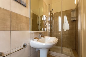 A modern bathroom with a glass shower enclosure, a white sink, and a handheld hair dryer mounted on the wall. - Urban Beach (Francavilla al Mare)