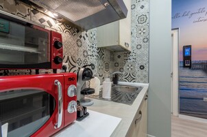 Una cocina con microondas rojo, cafetera y fregadero.