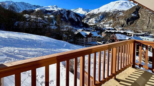A snow-covered mountain landscape with a wooden balcony overlooking a village.