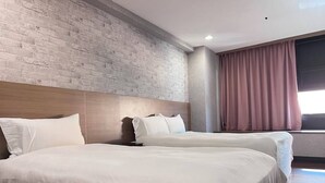 A hotel room with two beds, a brick wall, a wooden headboard, and a window with curtains. - GALA INN (Tainan)
