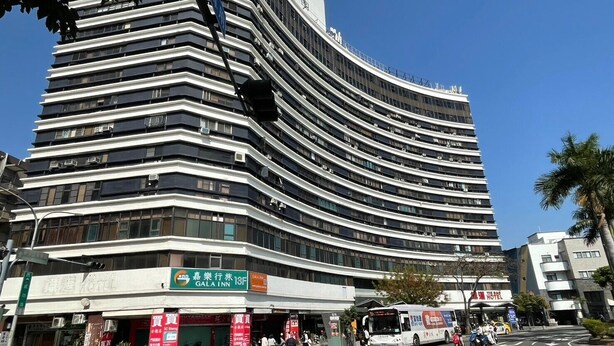 A modern hotel with a curved facade, multiple floors, and a prominent sign for the Gala Inn. - GALA INN (Tainan)