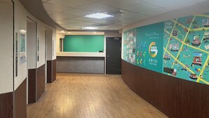 A hotel reception area with a green counter, wooden flooring, and a wall with a map and logo. - GALA INN (Tainan)