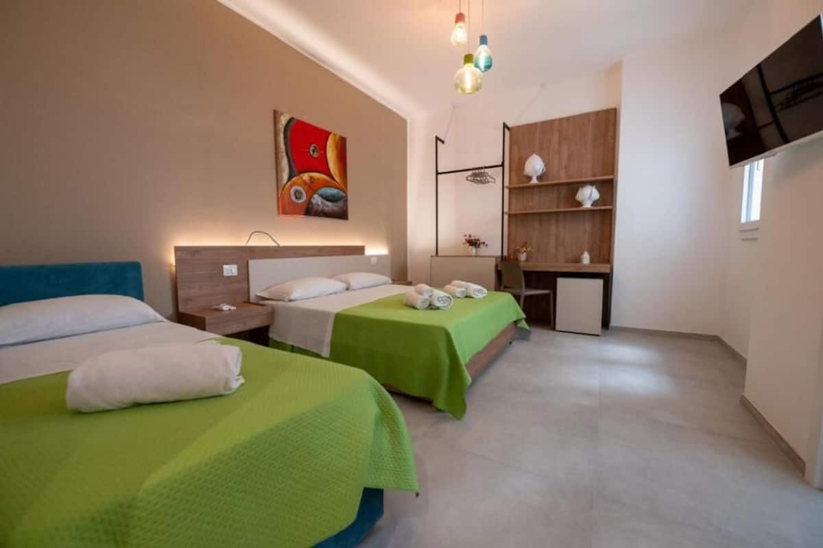 Een hotelkamer met twee bedden, een bureau, een televisie en een schilderij aan de muur.