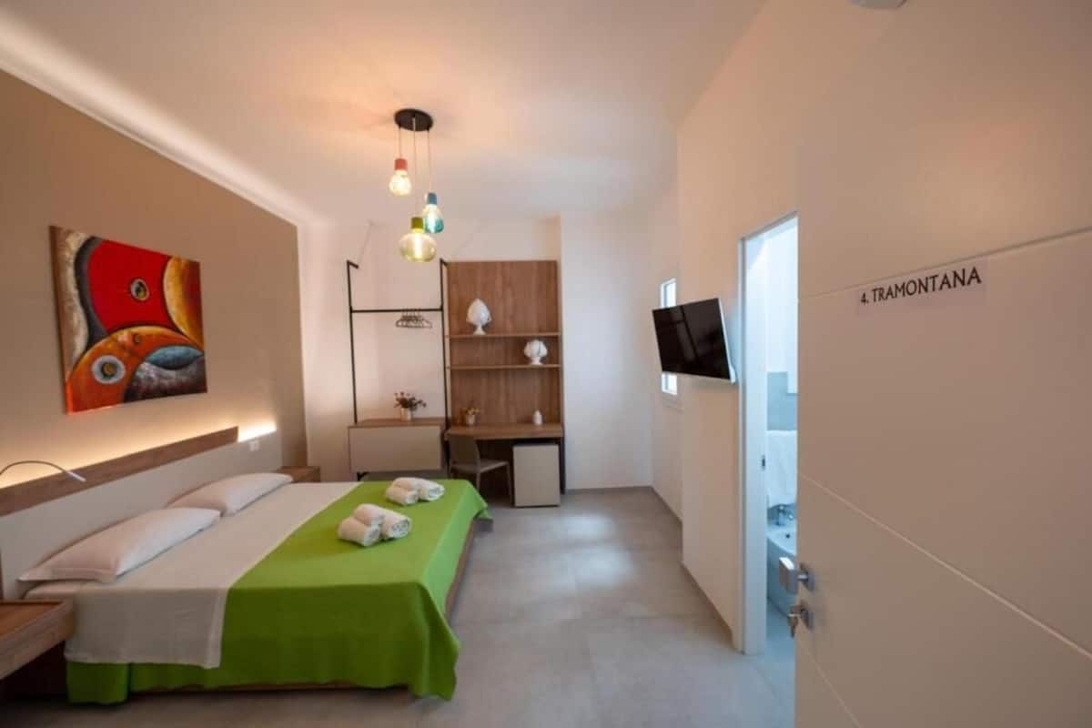 Een hotelkamer met een bed, bureau, televisie en een wandplank.