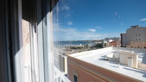 A view from a window overlooking a marina with boats, buildings, and a clear sky.