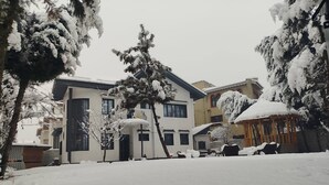 A snow-covered residential area with houses, a gazebo, and a tree. - Dilan Residency Villa -5 Bedroom- Centrally Heated (Srinagar)