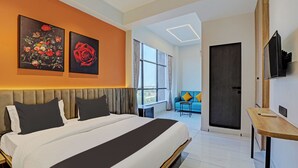 Quarto de hotel moderno com uma cama grande, uma mesa de escritório e obras de arte na parede.