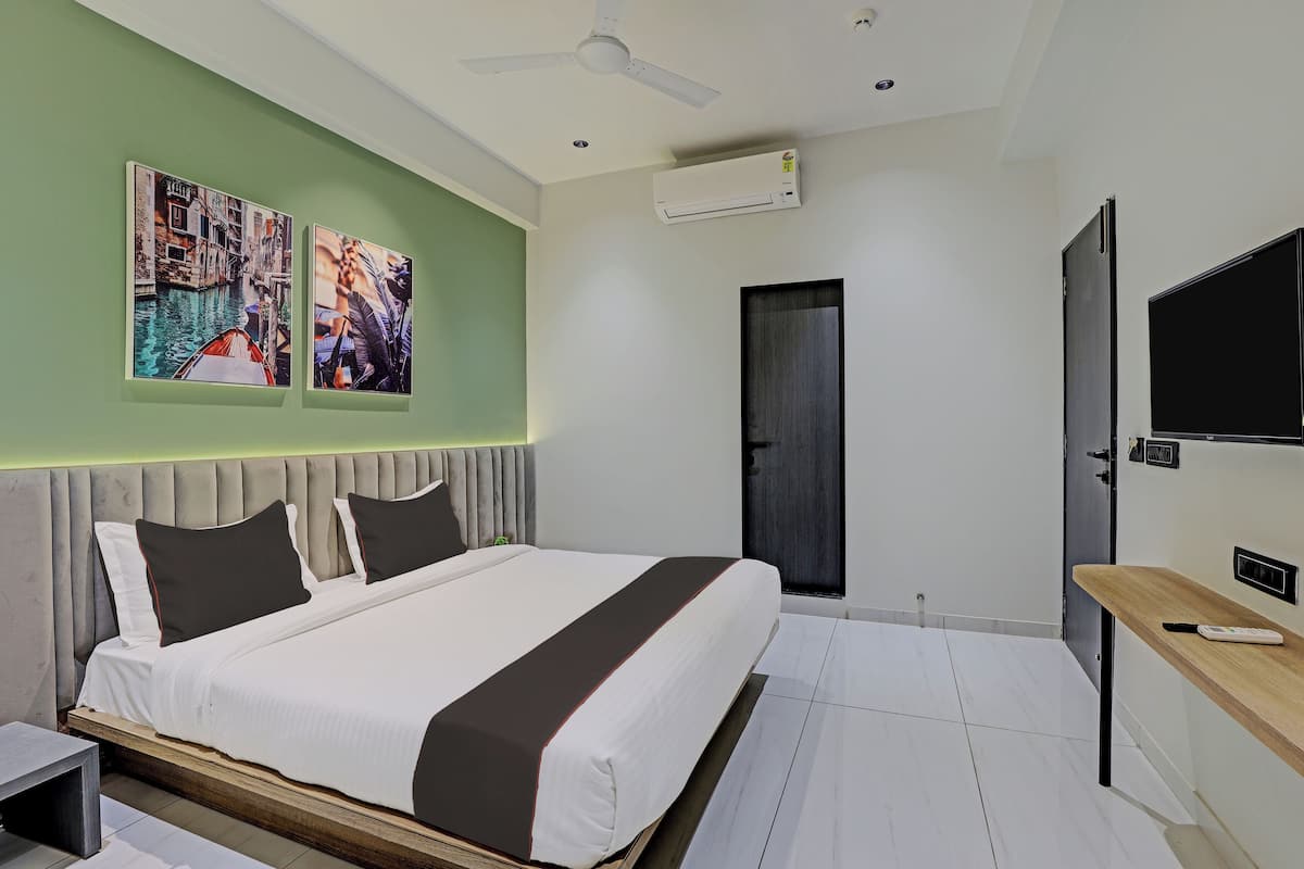 A modern bedroom with a bed, a TV, and artwork on the wall.