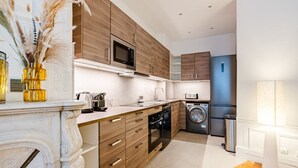 Een moderne keuken met houten kastjes, roestvrijstalen apparatuur, een inbouwoven en een wasmachine.