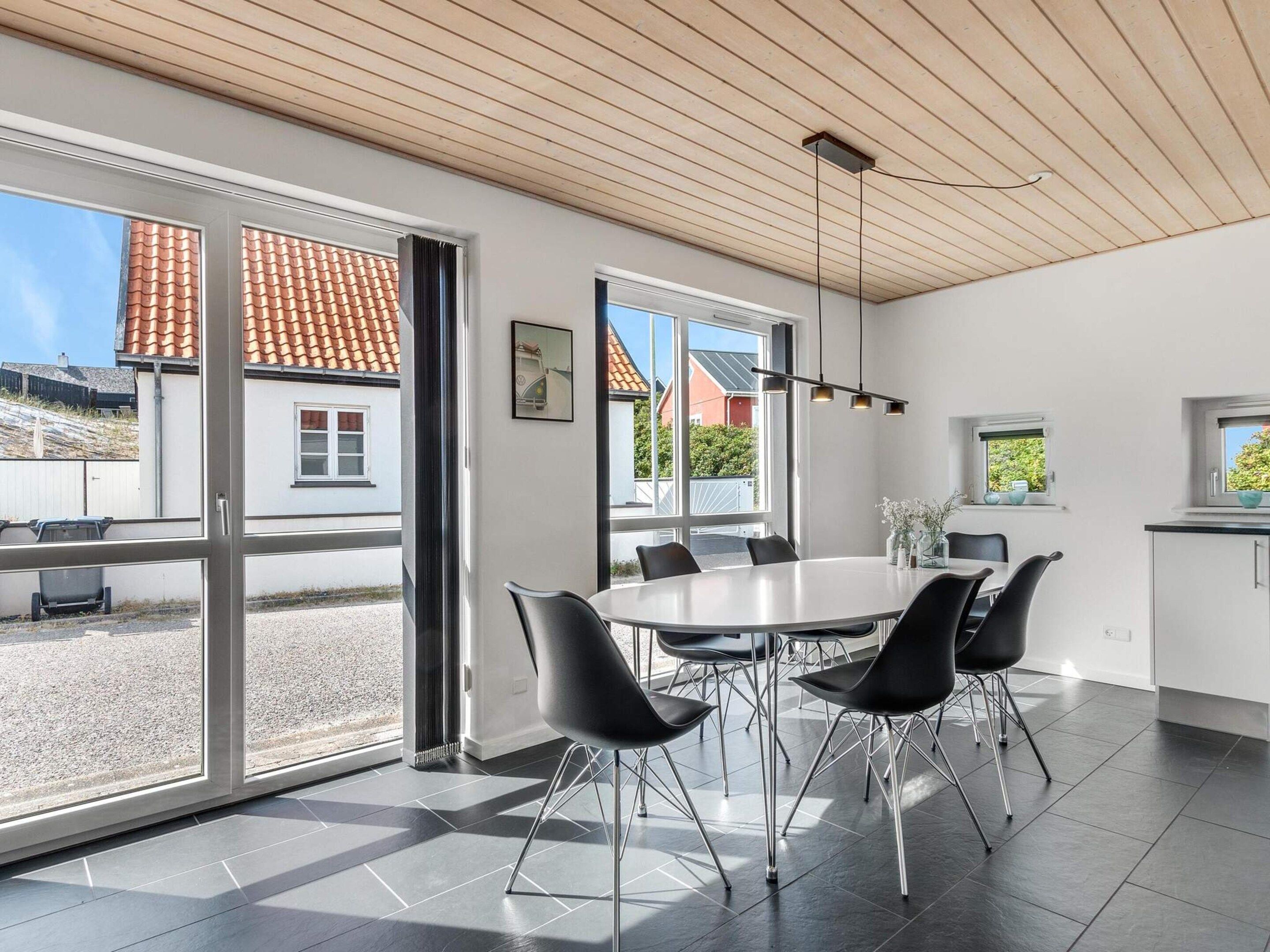 Een modern interieur met een ronde tafel, zwarte stoelen en grote ramen.