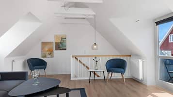 Et moderne loftværelse med skrå vægge, et stort vindue og udsigt til en rød bygning.