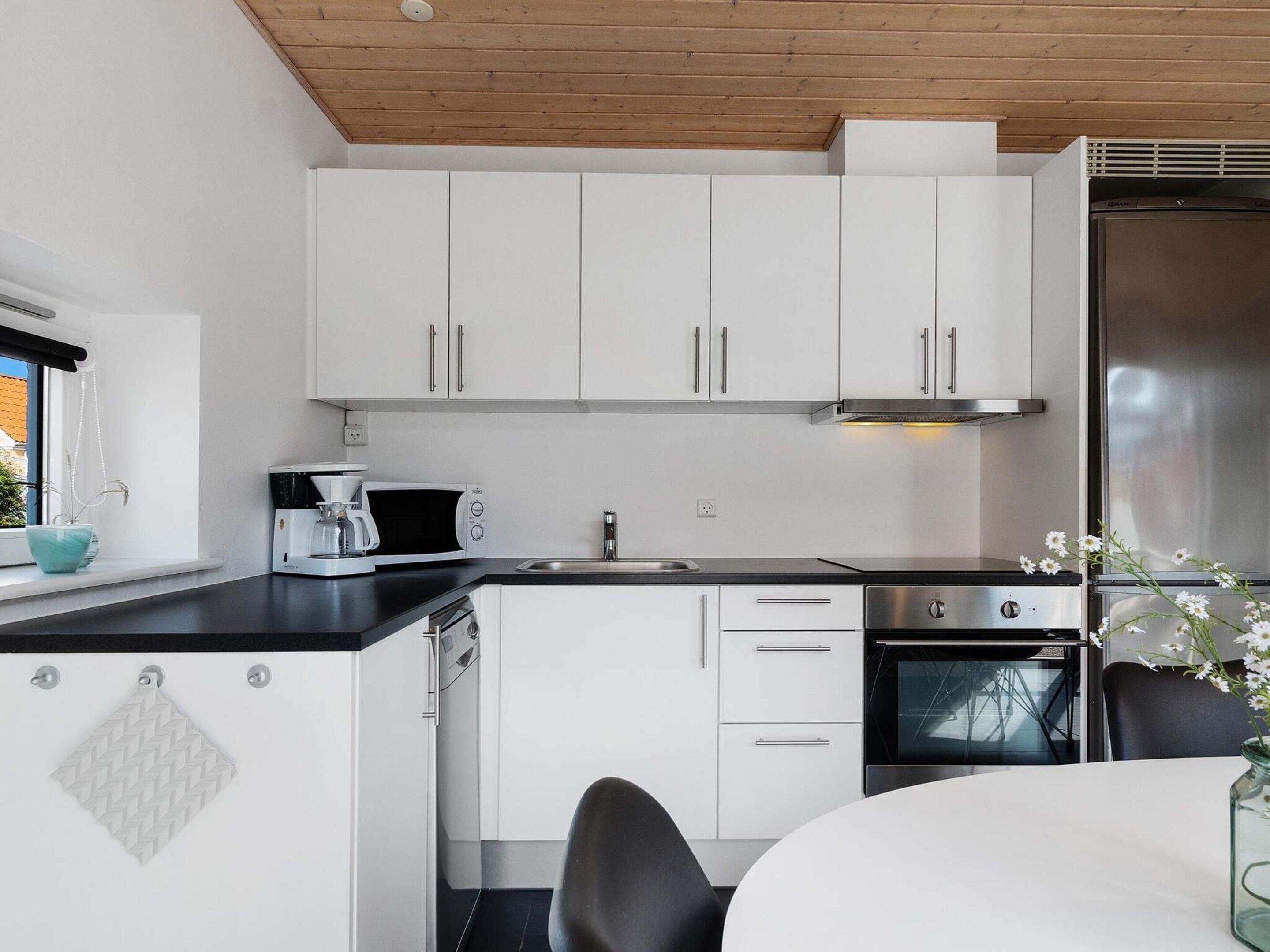 Een moderne keuken met witte kasten, een roestvrijstalen koelkast, een koffiezetapparaat en een spoelbak.