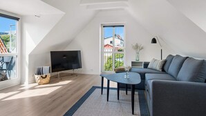 A modern living room with a TV, sofa, and a small table. - 5 Star Holiday Home in Lokken (Lokken)