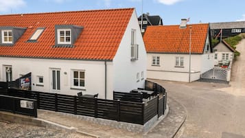 Hvide huse med orange tagsten, et sort hegn og en belagt vej.
