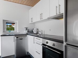 A modern kitchen with stainless steel appliances, white cabinetry, and a window with a view.