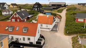 A coastal village with a mix of traditional and modern houses, a dirt path, and a view of the sea. - 5 Star Holiday Home in Lokken (Lokken)