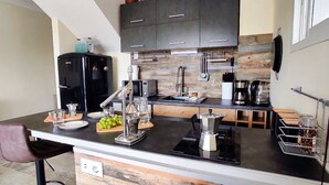 A modern kitchen with a black refrigerator, stainless steel appliances, and a wooden backsplash. - Casa Palmu apartment - A peaceful and relaxing oasis in Golf del Sur, Tenerife (Golf del Sur)