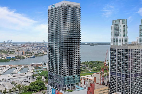 A high-rise building with a modern design, a marina with boats, and a clear view of the water.
