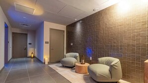 A hallway with two sofas, a wooden table, and a tiled wall.