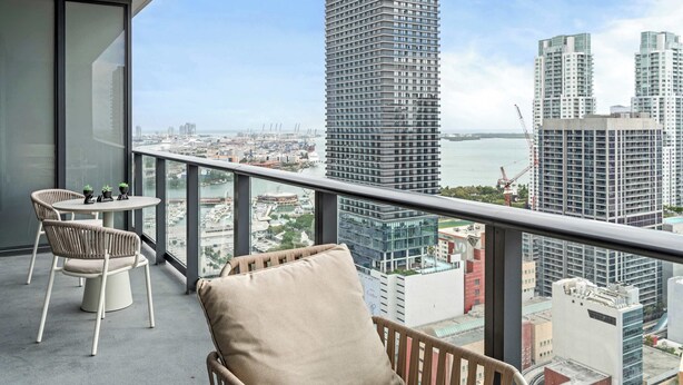 A balcony with a view of high-rise buildings and a body of water.