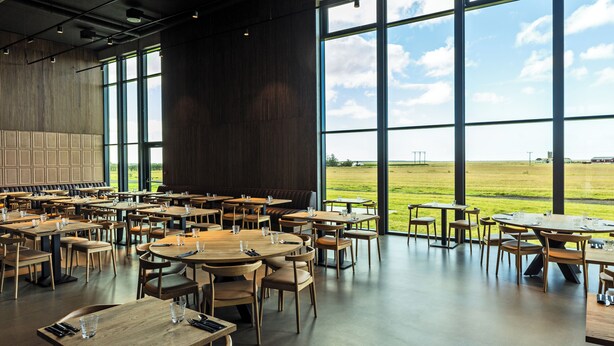A spacious dining area with multiple tables and chairs, large windows offering a view of the outdoors. - Hotel Loa (Rangárþing eystra)