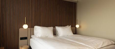 Un dormitorio moderno con cama, pared de paneles de madera y dos lámparas de noche.