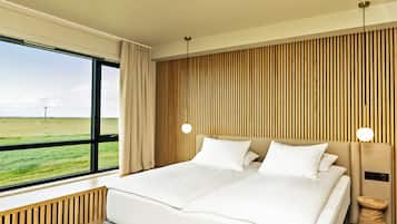 Una habitación de hotel moderna con una cama grande, vistas al campo y una pared de acento de madera.