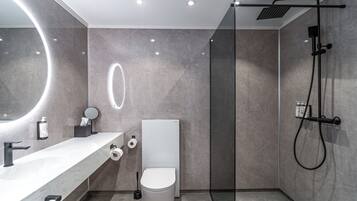 A modern bathroom with a white vanity, a round mirror, a toilet, and a shower area.