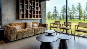 A modern living room with a sofa, two coffee tables, and a wooden shelving unit with decorative items. - Hotel Loa (Rangárþing eystra)