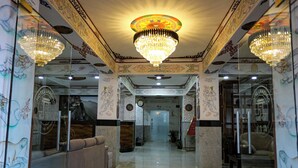 A hotel lobby with ornate ceiling decorations, chandeliers, and traditional wall art. - Hotel Lhading (Thimphu)