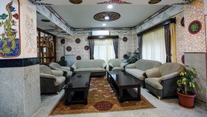 A traditional room with a sofa set, a coffee table, and a potted plant. - Hotel Lhading (Thimphu)