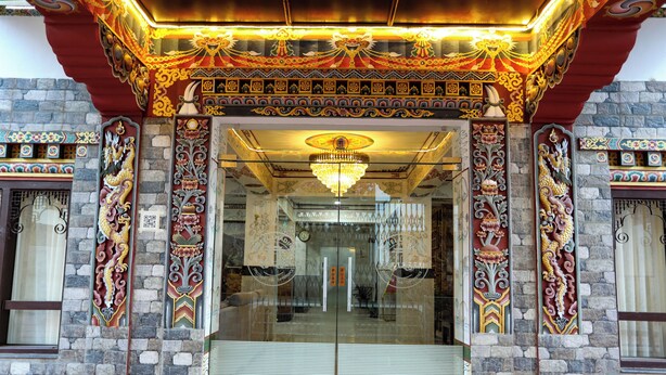A building entrance with ornate decorations, a glass door, and a chandelier. - Hotel Lhading (Thimphu)