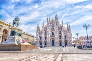 A grand cathedral with intricate Gothic architecture, a prominent statue in front, and a wide plaza with people walking. - Guesthouse - Metro M1 Sesto Rondò (Sesto San Giovanni)