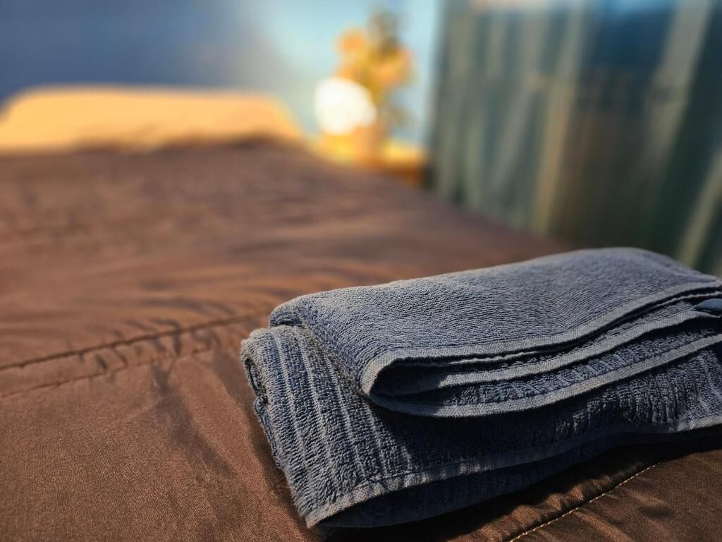 Une serviette bleu foncé, soigneusement pliée, est posée sur un couvre-lit marron.