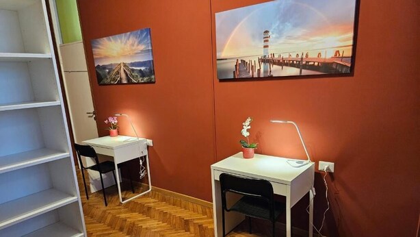 A room with two desks, a chair, a shelf unit, and two paintings on the wall. - Guesthouse - Metro M1 Sesto Rondò (Sesto San Giovanni)