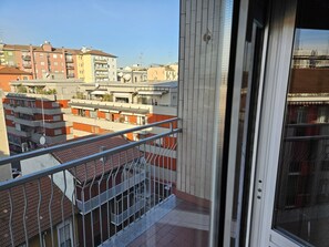 A balcony with a metal railing overlooking a residential area with multi-story buildings. - Guesthouse - Metro M1 Sesto Rondò (Sesto San Giovanni)