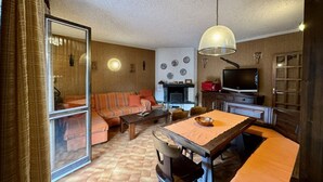A living room with a sofa, dining table, chairs, a television, and a fireplace. - Vacation House Caspoggio.Apartment near local places of interest (Caspoggio)