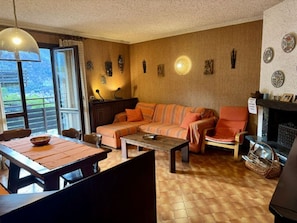 Een woonkamer met een bank, fauteuils, een salontafel en een open haard.