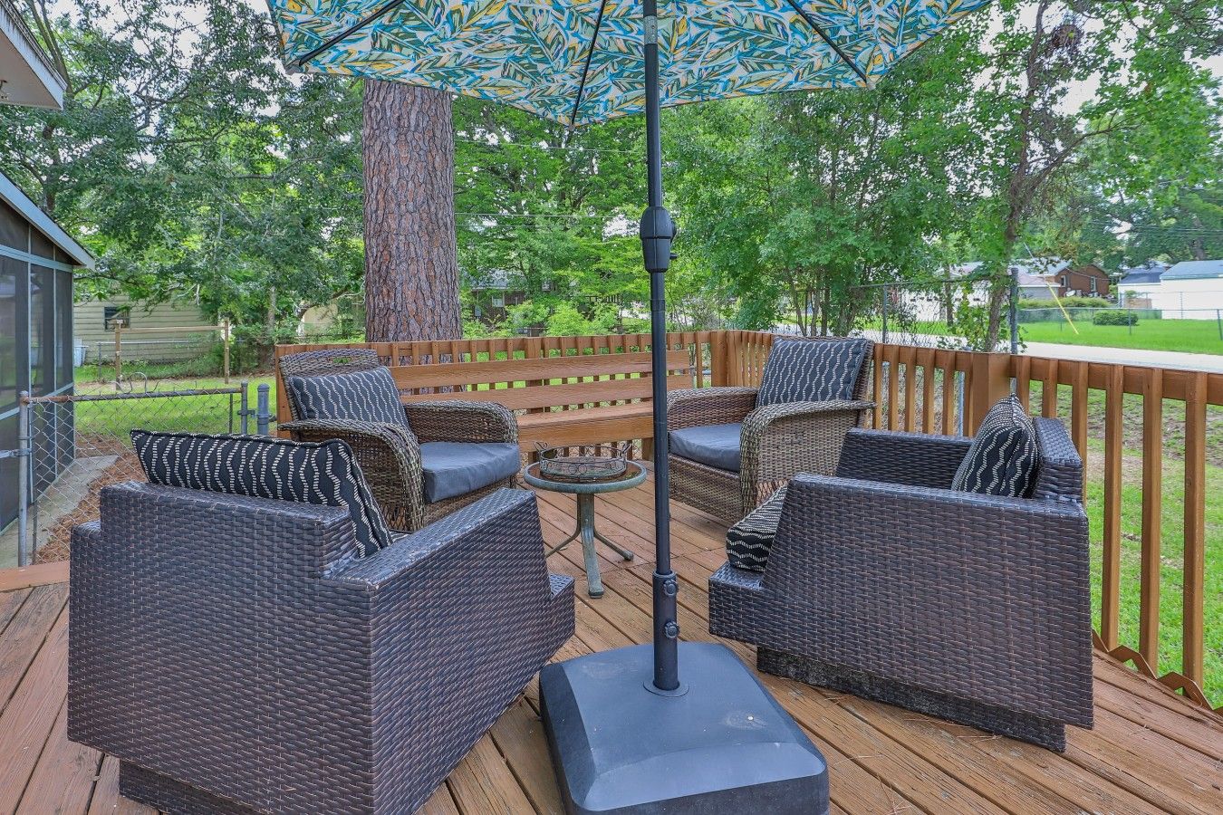 An outdoor deck with wicker furniture, a wooden bench, and a metal pole.