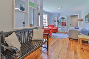 A living room with a wooden bench, red chairs, a bookshelf, and a door. - Aralia-5Min. to Williams-Brice/10Min. to Ft.Jackson (Columbia)