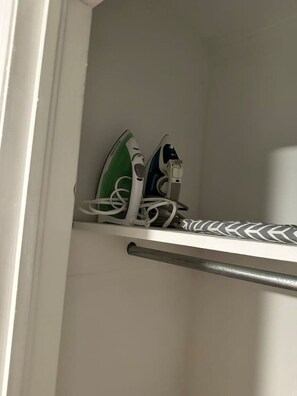 Un baño con un perchero que sostiene dos toallas blancas y una toalla verde y blanca a rayas.