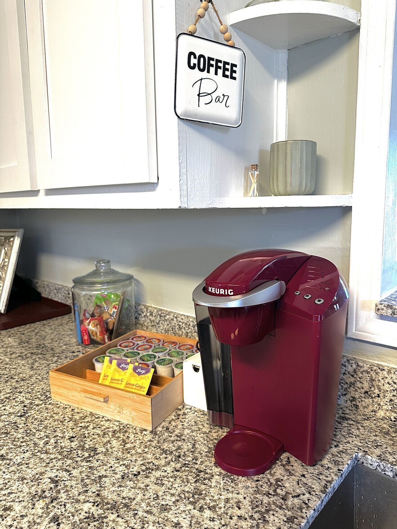Une cuisine équipée d’une machine à café, d’un panneau indiquant un bar à café et d’une boîte de dosettes de café.