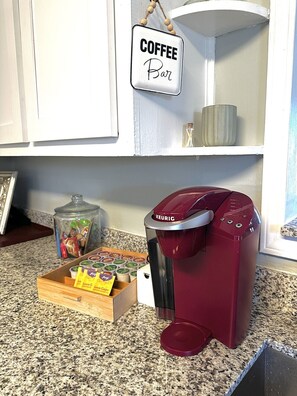 Una cocina con una cafetera, un letrero de cafetería y una caja de cápsulas de café.