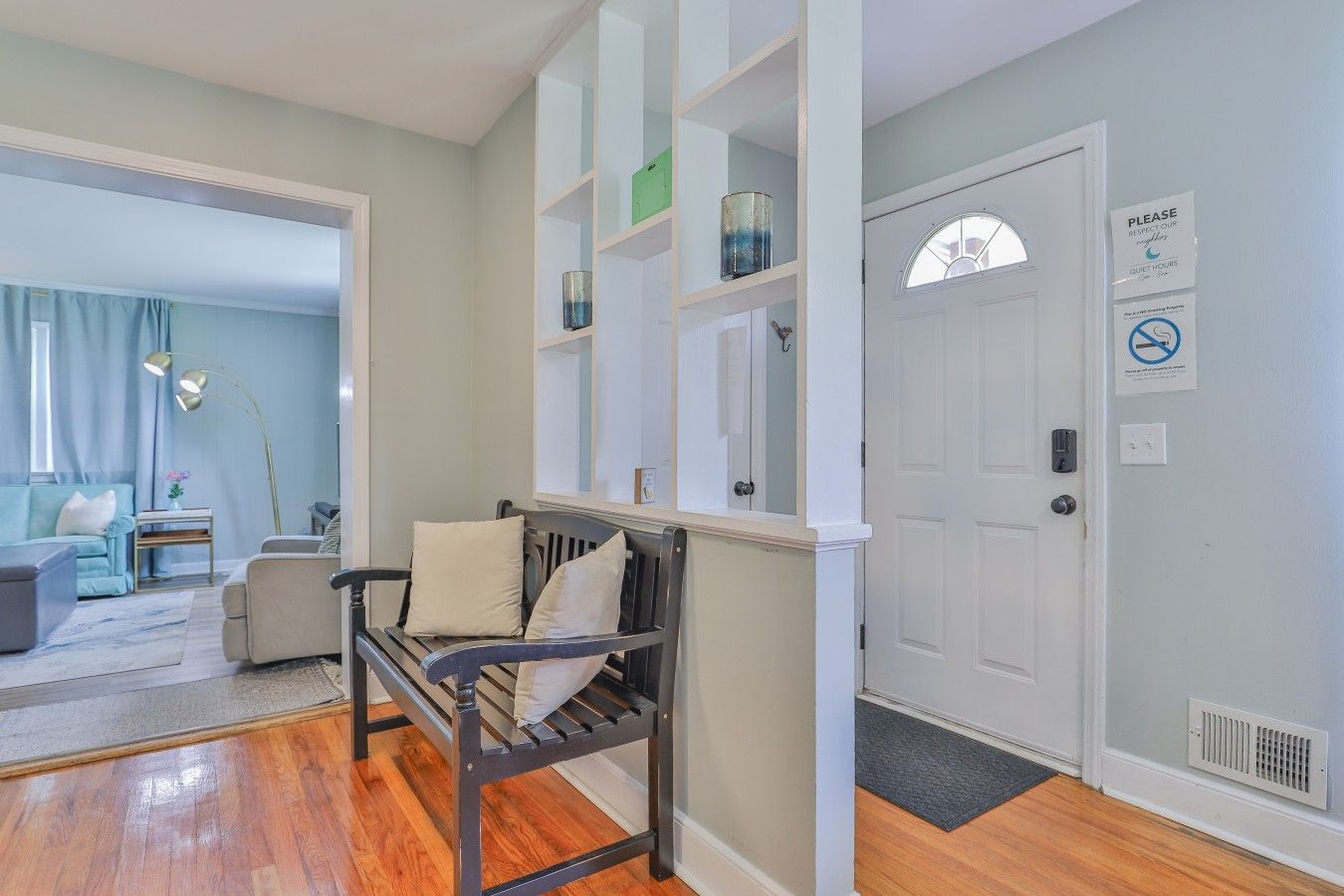 A room with a wooden bench, a white door, and a sign indicating quiet hours.