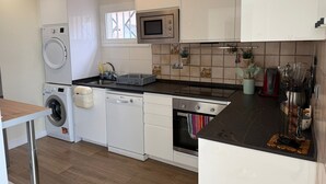 Eine kleine Küche mit Waschmaschine, Geschirrspüler, Mikrowelle und Backofen.
