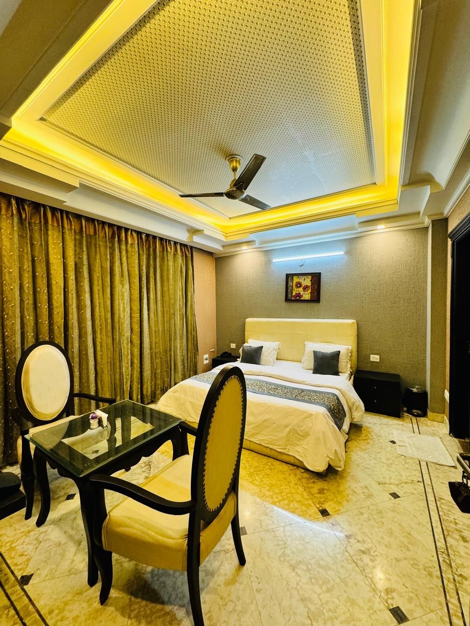 Habitación de hotel con cama, una mesa, una silla, un ventilador de techo y un espejo.